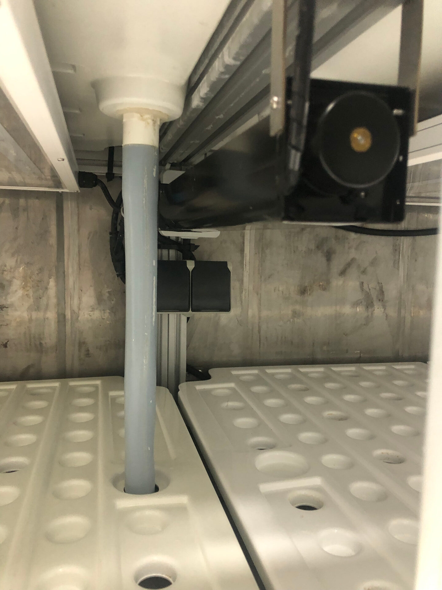 Grow trays with the drain pipe running from an upper tier down to the next